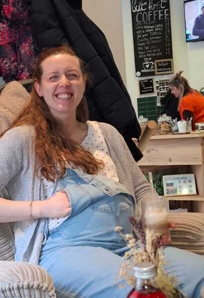 Lachende Schwangere sitzt im Nährcafé bei ONE DAY e.V.